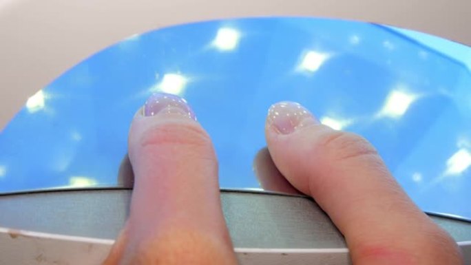 女人在紫外线下干燥拇指指甲上的基础凝胶