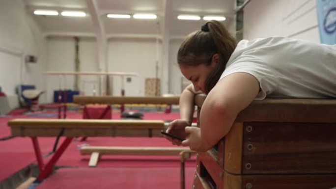 女子体操运动员，训练后放松身心，同时用手机上网