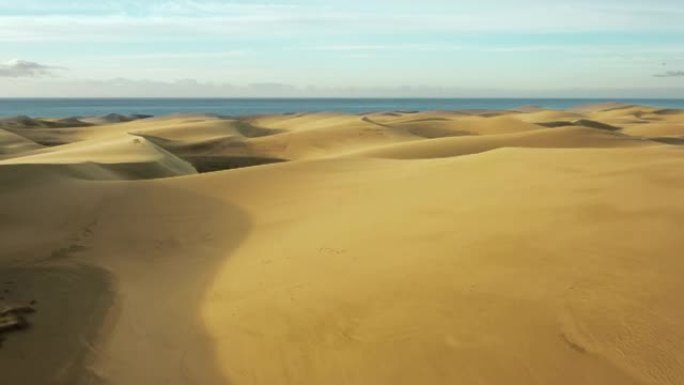 炎热干旱沙漠中的金色沙丘。飞越沙质沙漠到达水面。