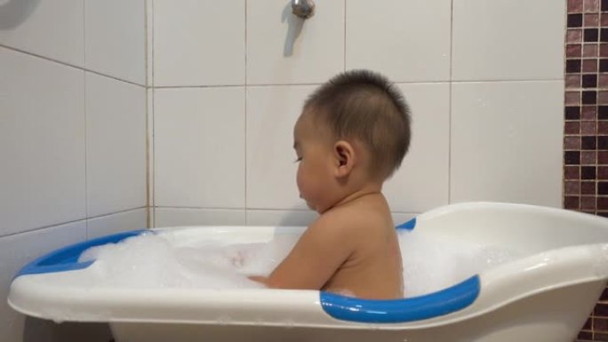 小孩子有趣的在家里的浴室内部用肥皂泡洗澡