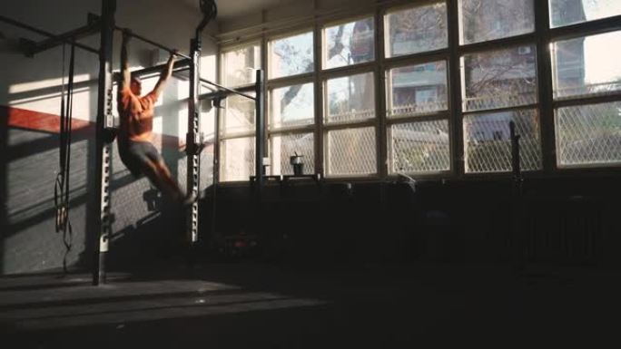 年轻的健身男子在健身房做蝴蝶引体向上