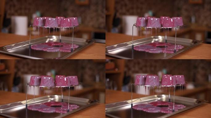 糕点厨师将镜子糖霜倒在蛋糕上。红釉从架子上流下。在厨房工作的专业糖果制造商