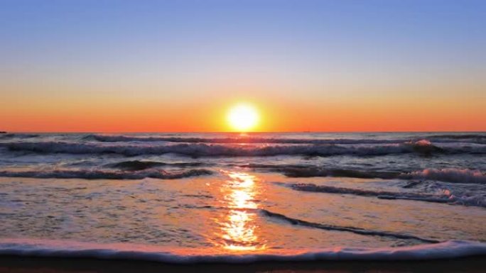 五颜六色的海洋海滩日出。海浪洗沙。