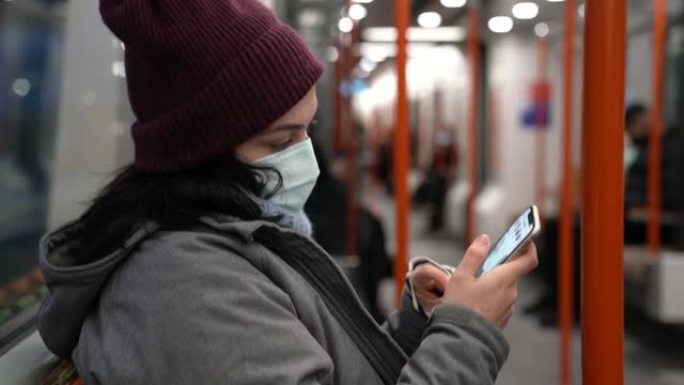 在火车内使用智能手机戴口罩的女人