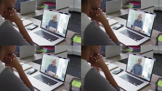 非裔美国妇女的中部与办公室的男同事在笔记本电脑上进行视频通话