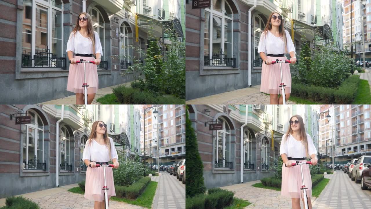 穿着粉色裙子的美丽微笑女人在城市街道上骑踏板车的4k视频