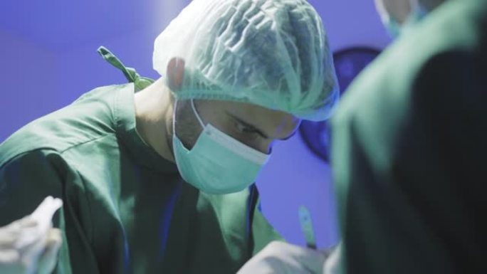 一位在压力下工作的外科医生，病情最严重的患者躺在医院手术室的床上，以挽救生命，在妇女协助下共同挽救生