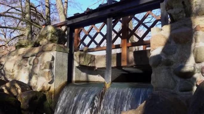 在阳光明媚的早晨，运河上有齿轮的水闸控制装置，瀑布和岩石溪流在下面