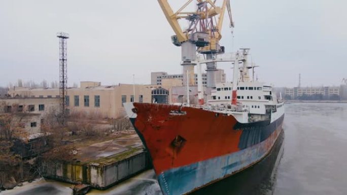 废弃沉没的生锈船多年停泊在港口，货物多吨位起重机和商业建筑