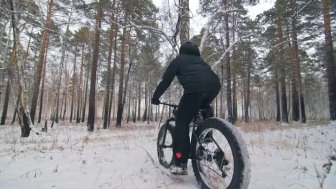 专业极限运动员骑自行车的人在户外骑胖自行车。骑自行车的人在冬天的雪林里骑。男人确实在戴着头盔和眼镜的