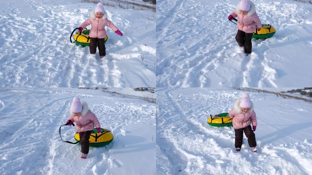 一个小女孩走过雪地，用她的管子拉着