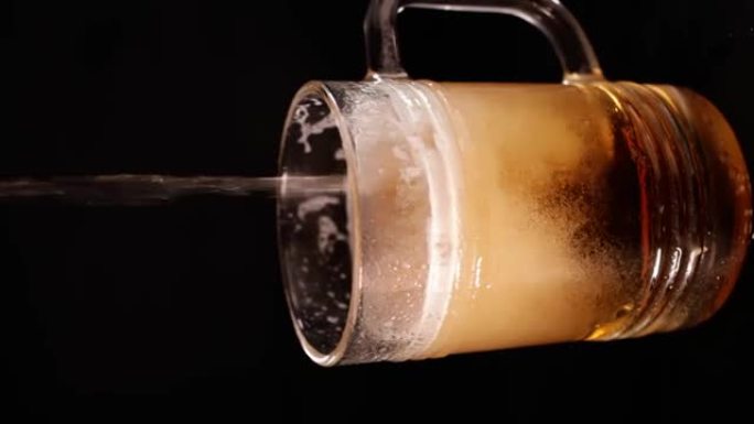 玻璃啤酒杯。不含酒精的啤酒，低调，深色背景。啤酒随着涓涓细流倒入杯子里。垂直视频