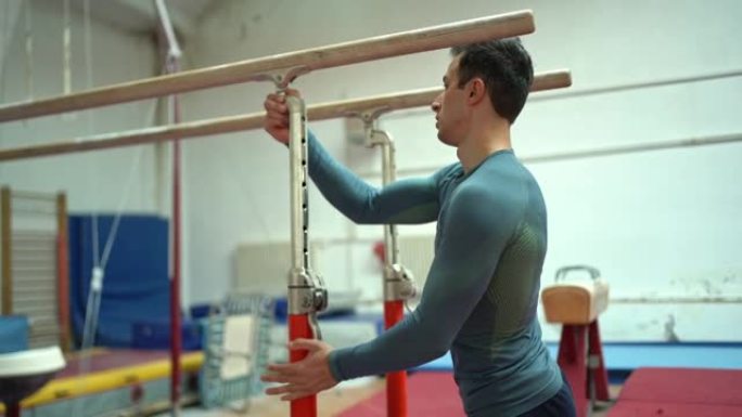 男运动员，体操运动员，在训练过程中调整双杠的高度