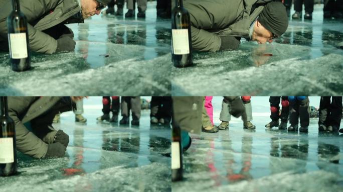 根据当地的传统 “与贝加尔湖接吻”，一名男子在冬天从贝加尔湖的冰洞里喝葡萄酒。