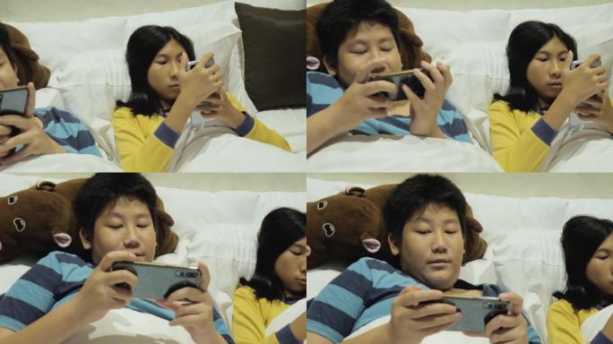 快乐的亚洲儿童在假期期间在酒店房间的床上一起玩网络游戏，生活方式理念。