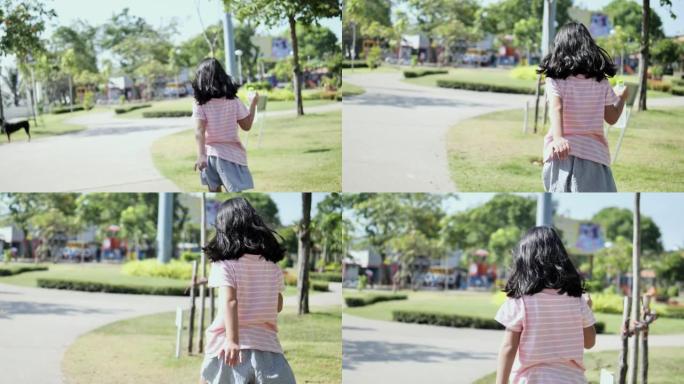 在阳光明媚的日子里，女孩在公园户外散步，拿着一瓶水，生活方式的概念