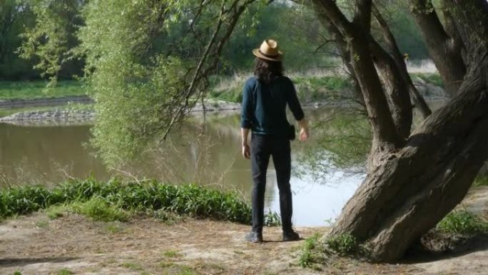 年轻人戴上帽子，站在大自然中，穿着蓝绿色长袖t恤