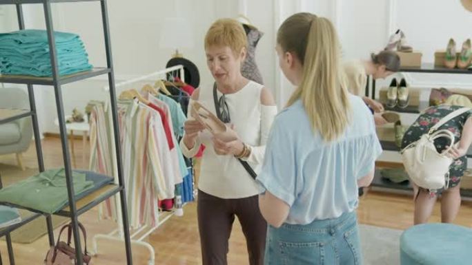 女售货员协助女性顾客在时装店购物