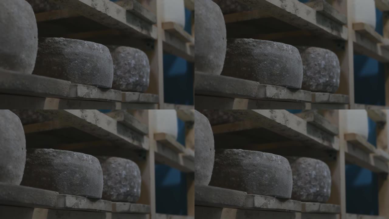 架子上的成熟室中有许多发霉的硬奶酪。蓝纹奶酪饼坐在木架子上，成熟了几个月甚至几年。多莉开枪。特写