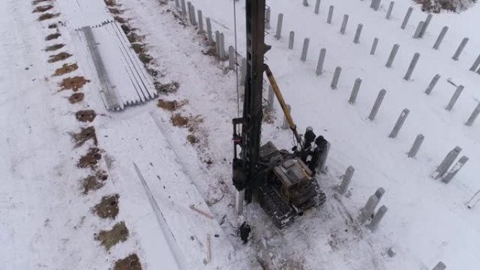 在冬季施工现场工作的桩孔机的空中无人机视图