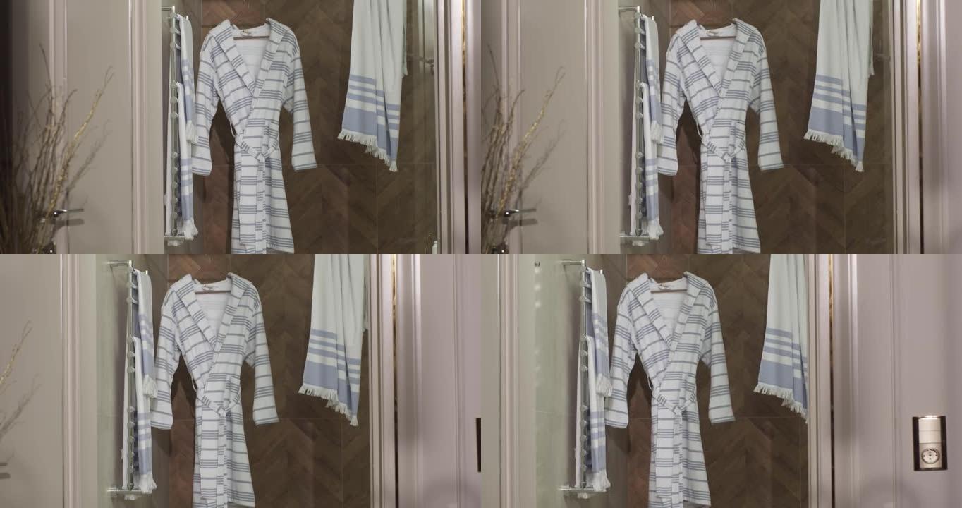 带灰蓝色条纹的浴袍和淋浴毛巾挂在淋浴间