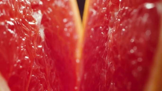 4k微距视频，将水和滴落的水滴切成两半，新鲜美味的葡萄柚。有机食品和健康营养的完美抽象镜头。