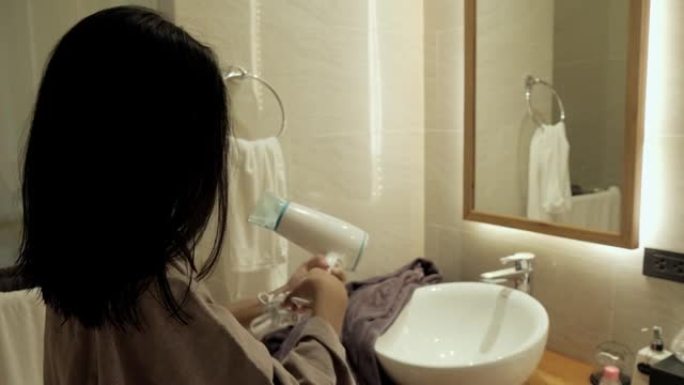 快乐的亚洲女孩在酒店房间洗澡后完成了吹风机的使用，生活方式理念。