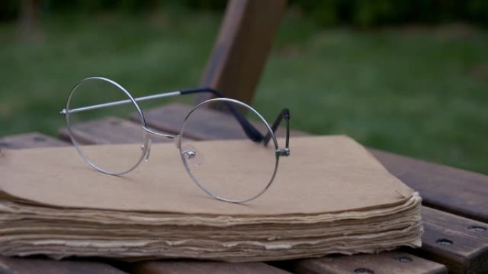 春天花园里的木椅上的旧书和眼镜