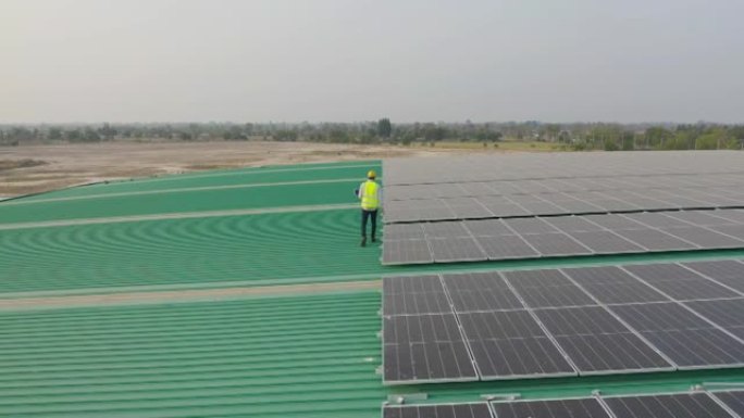 在工厂工业中，屋顶上有太阳能电池板或太阳能电池的工程师或工人，人的空中俯视图。发电厂，可再生能源。电