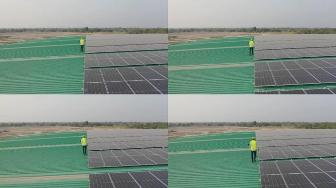 在工厂工业中，屋顶上有太阳能电池板或太阳能电池的工程师或工人，人的空中俯视图。发电厂，可再生能源。电