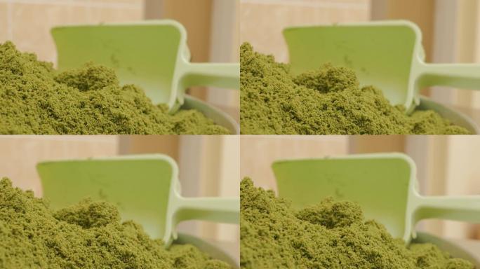一堆磨碎或压碎的绿色开心果种子和一个绿色糕点勺。一碗开心果面粉。特写，多莉拍摄。4k