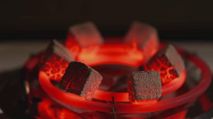 在电加热器上加热的水烟烧红煤，在家准备水烟，灰烬，将相机镜头从前景聚焦到背景