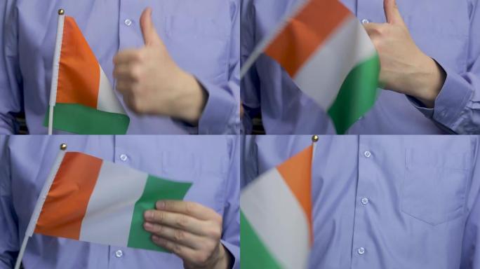 一名男子举着爱尔兰国旗挥舞着，竖起大拇指。