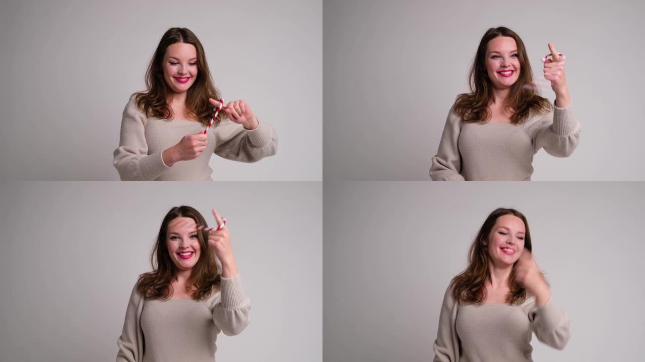 一个微笑的女人玩圣诞条纹棒棒糖的有趣视频。