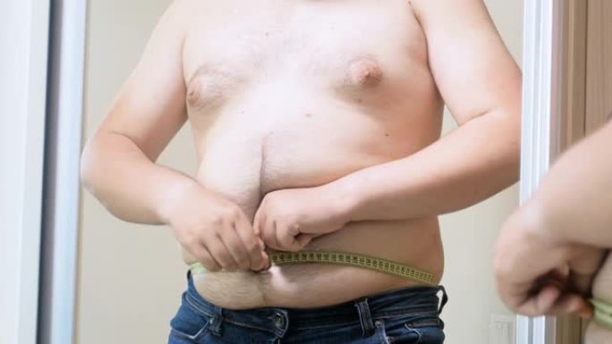 4k视频超重男子试图用镜子上的黄色卷尺测量他的大肚子
