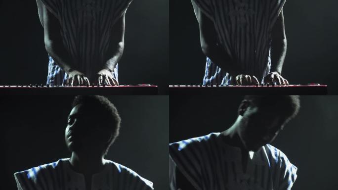 非裔美国人在黑暗烟熏工作室的舞台上演奏钢琴合成器的剪影。脸上带有白色民族图案的黑人音乐家在灯光的背景