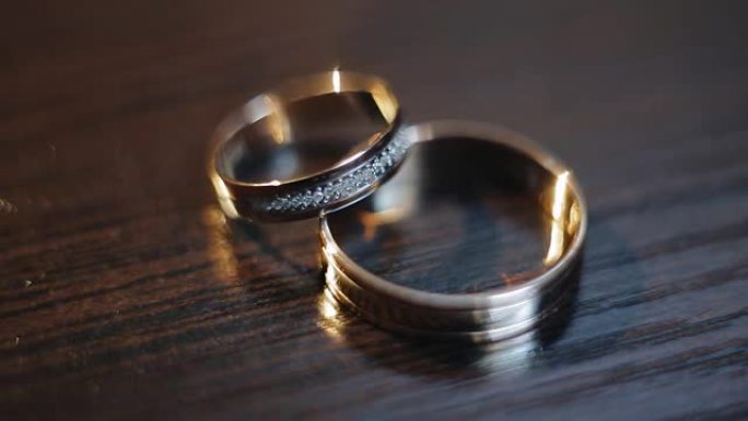 和金结婚戒指躺在木质表面上。戒指上的光的美丽亮点