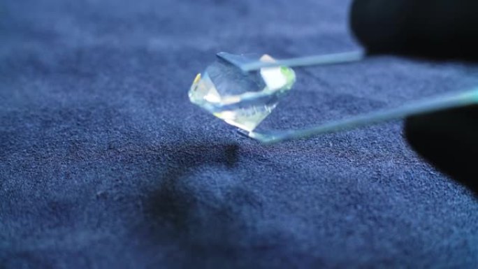 珠宝商使用银镊子和黑色乳胶手套检查大半透明钻石，以验证它是真品还是假的