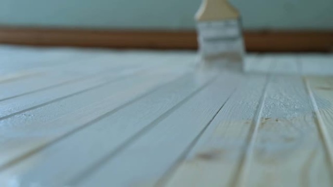 女孩用慢动作的白色油漆画木地板，特写