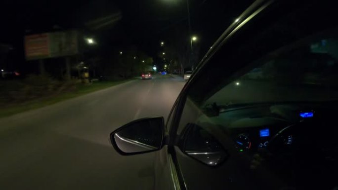 一名男子晚上开着汽车在城市里转转，车窗里倒映着城市照明。