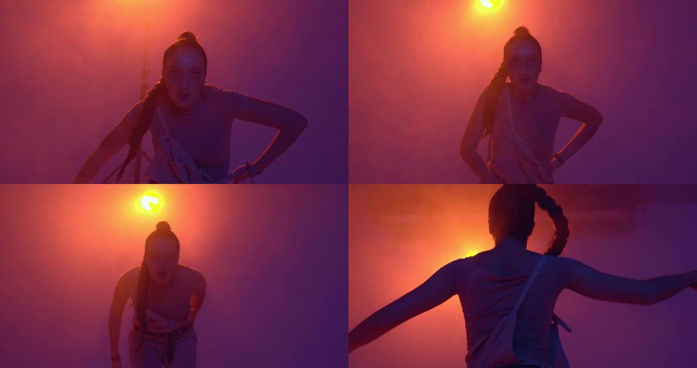 年轻的混血儿女孩在演播室里用烟在聚光灯下跳舞热热情的火热舞蹈。表情和节奏