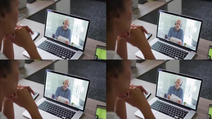 非裔美国妇女的中间部分在办公室的笔记本电脑上与男同事进行视频通话