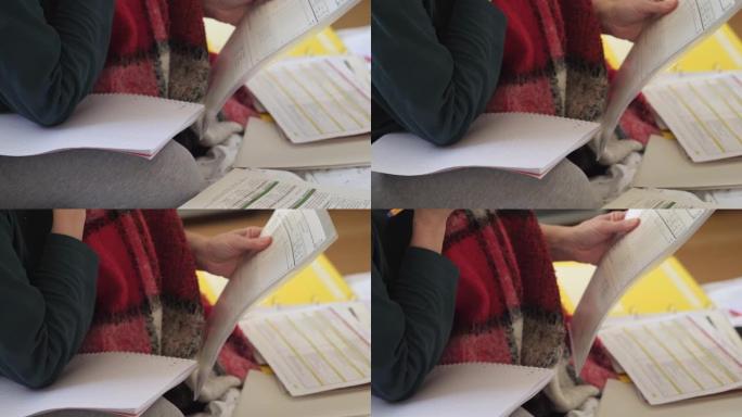 用散落的纸和笔记本在腿上的毯子在沙发上学习
