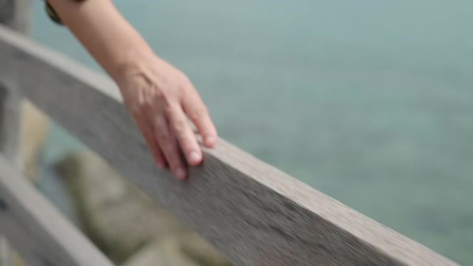 暑假，女人在海上的木桥扶手上触摸和滑动