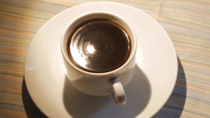 白色的一杯黑咖啡在地震中摇晃。杯子里的咖啡因强烈的颤抖而颤抖。特写顶视图。4k