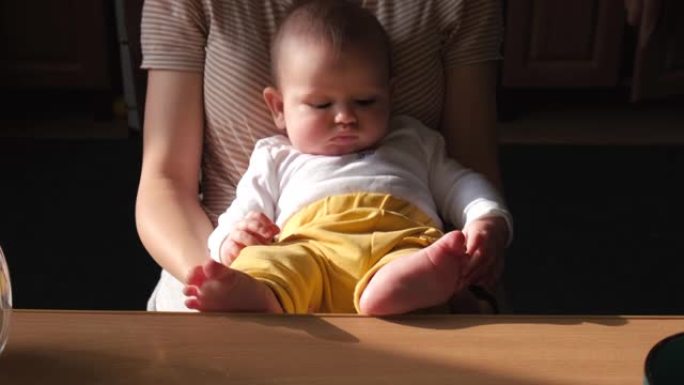 高加索母亲将刚出生的婴儿抱在桌子附近的膝盖上