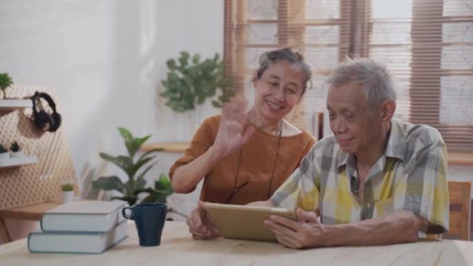 亚洲活跃的老年人使用数字平板电脑在家中进行视频通话会议