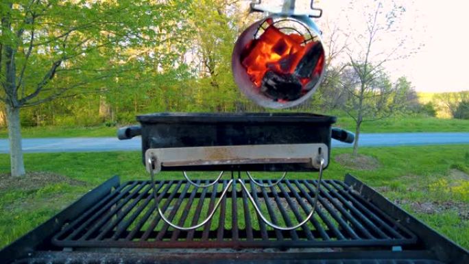 将球形的热木炭从木炭烟囱启动器倒入烤架上