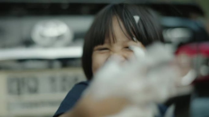 亚洲小女孩喜欢在前院洗车。