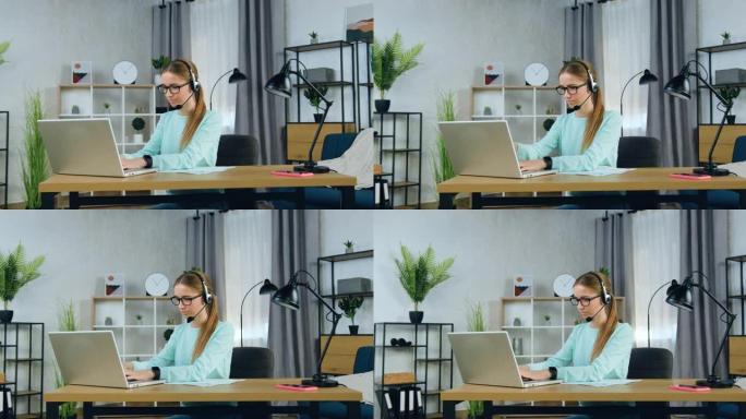 迷人的自信集中的20岁女孩戴着耳机坐在电脑前写大学或大学的家庭任务，慢动作